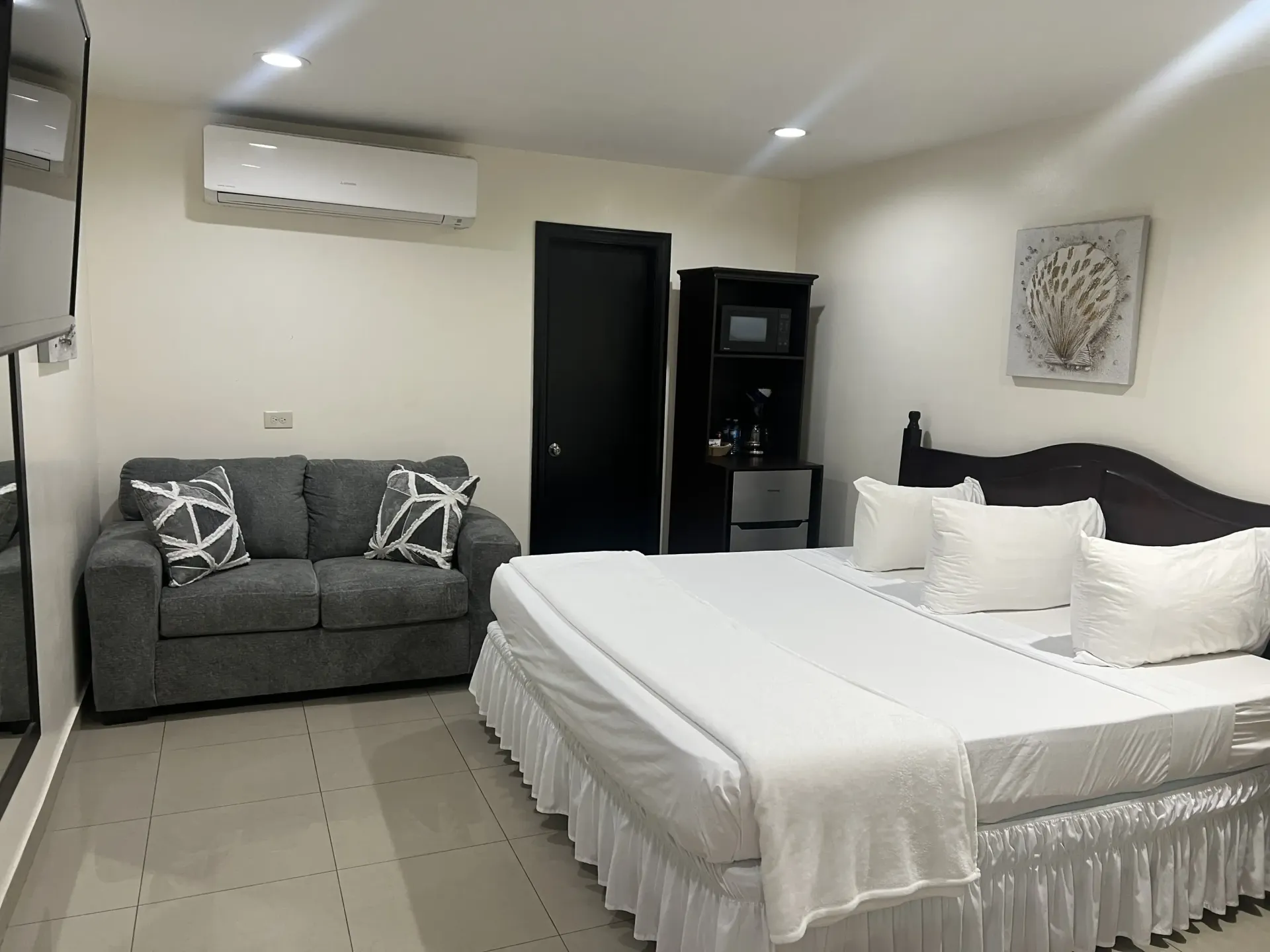 Hotel room with a bed, small sofa, and a microwave on a cabinet.