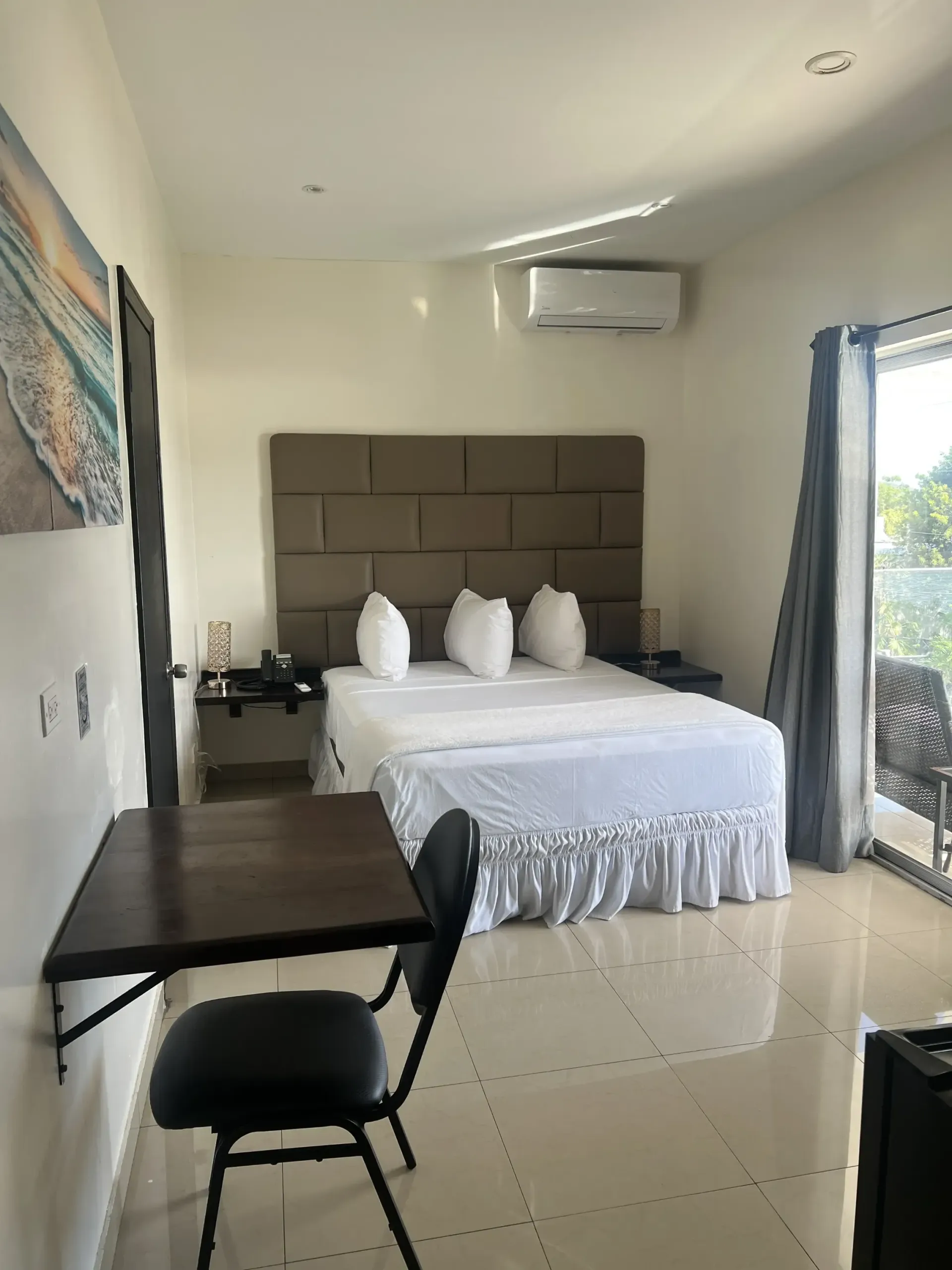 Bedroom with bed, desk, chair, and access to a patio with open blinds.