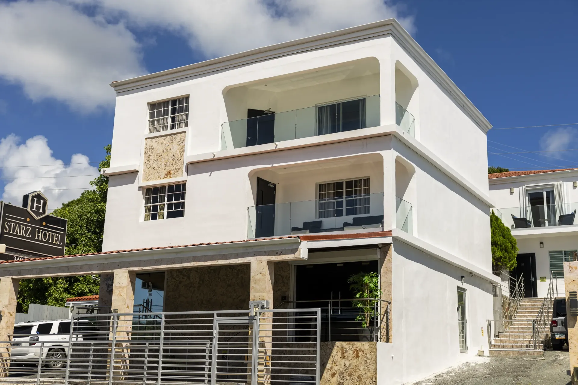 Three-story white building with balconies; stone accents on the first floor.
