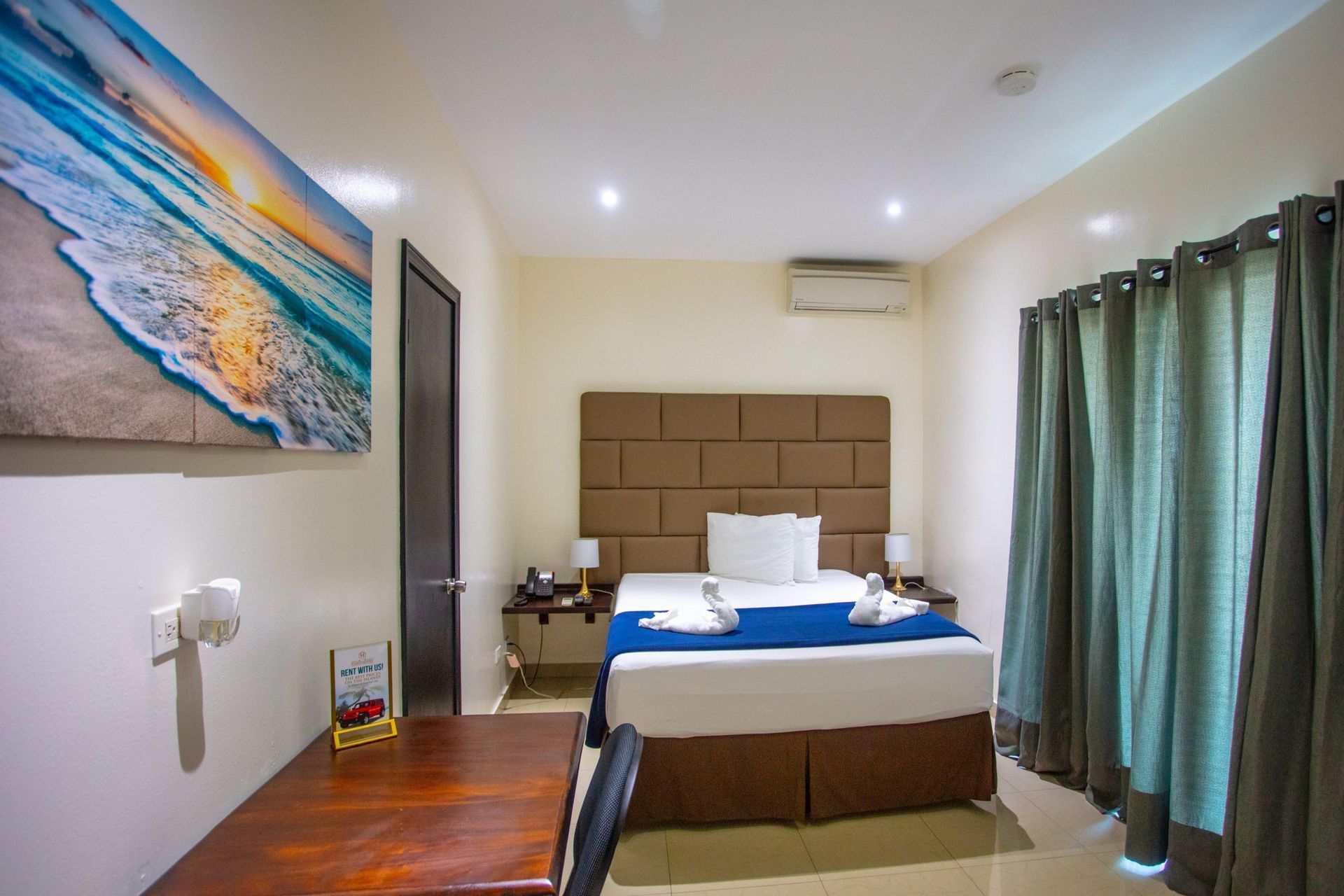 Hotel room with a king-size bed, desk, brick accent wall, and a TV.