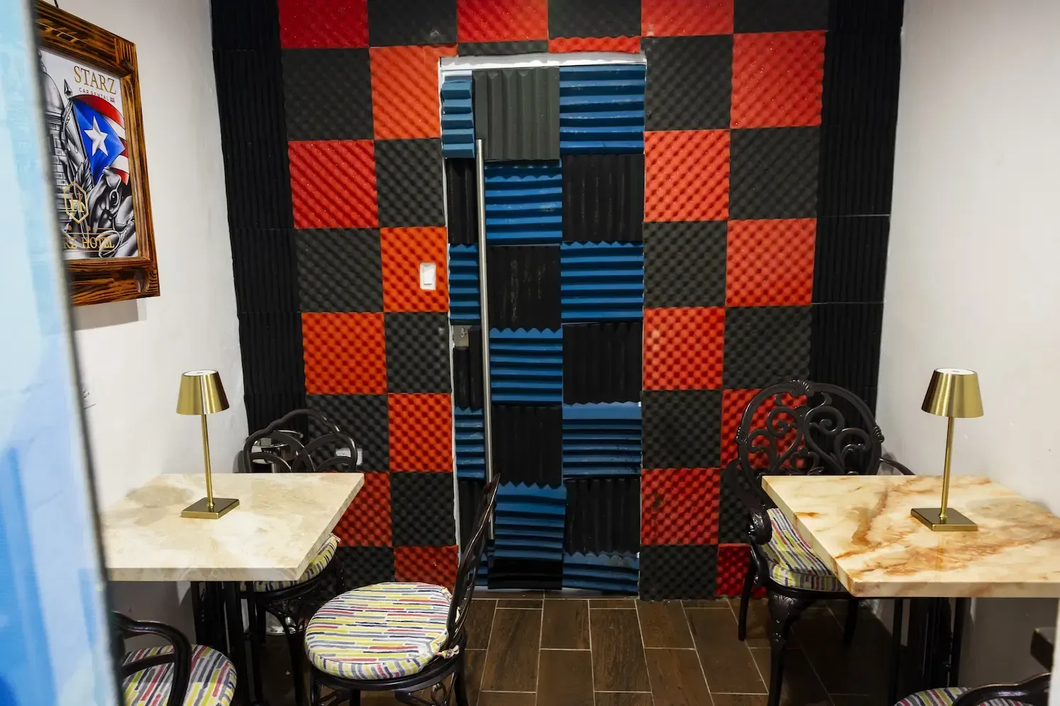 Small room with soundproofing, tables, chairs, and lamps. Wall art visible.