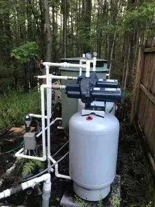 Outdoor water pump and pressure tank installed among trees in a wooded area