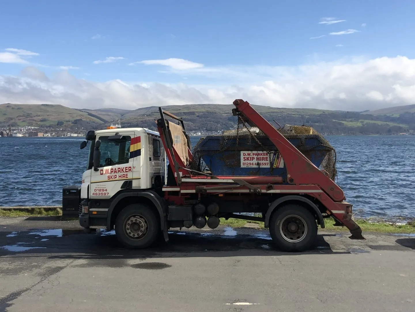 White lorry with blue skip on back