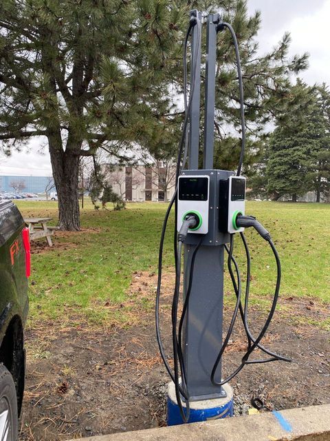 Borne de recharge pour véhicules électriques à deux ports sur un parking.