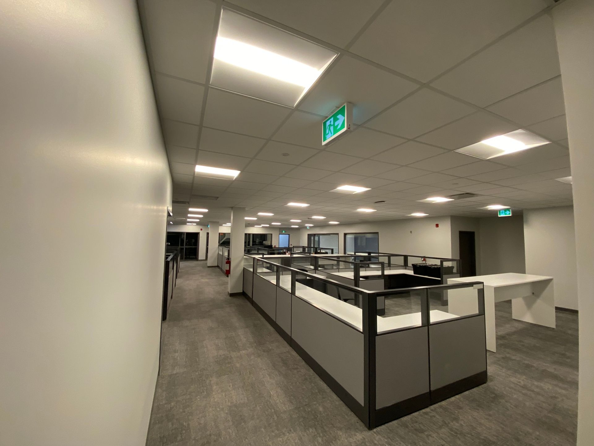 Intérieur de bureau vide avec des cloisons, des murs blancs et un éclairage zénithal vif.