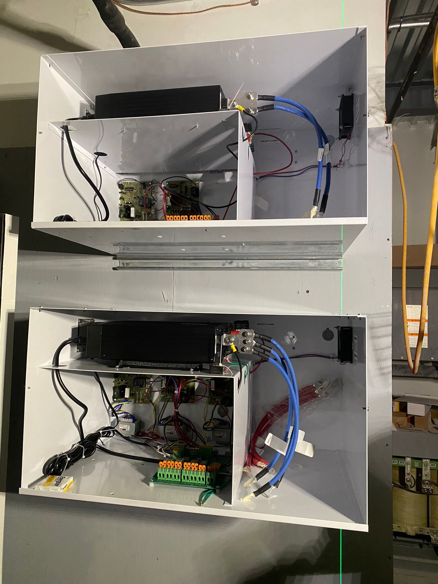 Deux boîtiers métalliques ouverts, fixés au mur, contenant des composants électroniques avec câblage.
