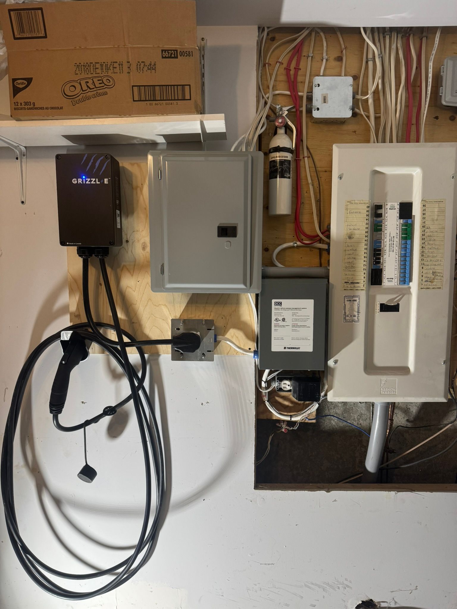 Tableau électrique, borne de recharge pour véhicule électrique, boîtes de jonction et câblage fixés au mur.