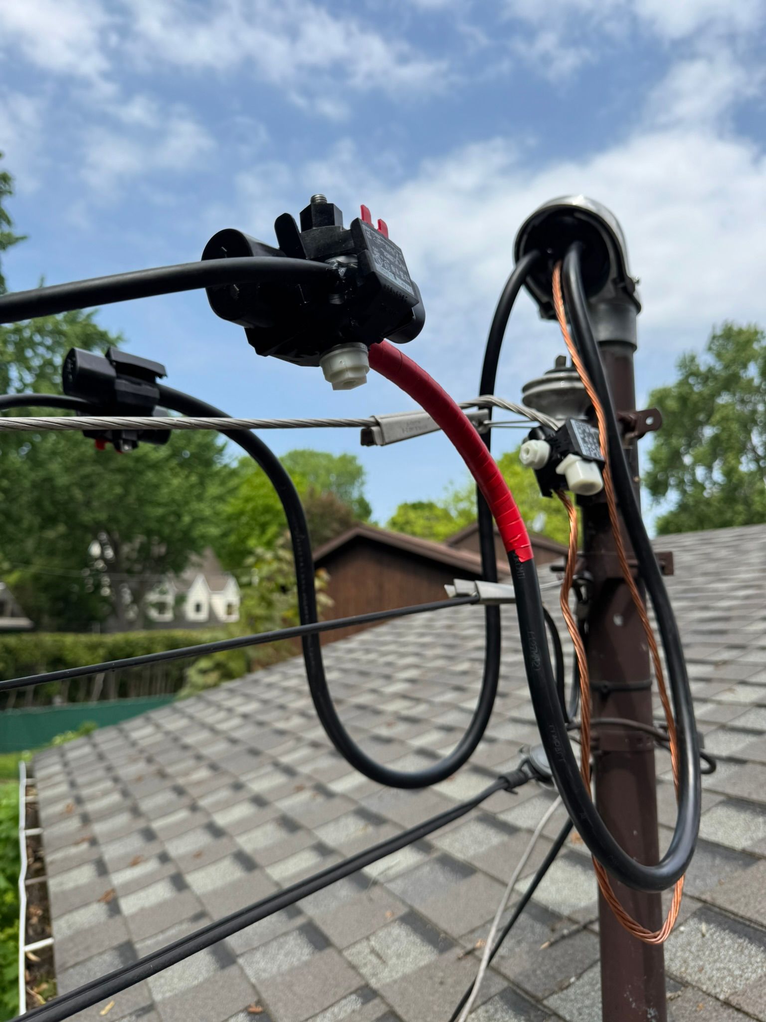 Composants électriques sur un poteau relié à des lignes électriques, au-dessus du toit d'une maison.