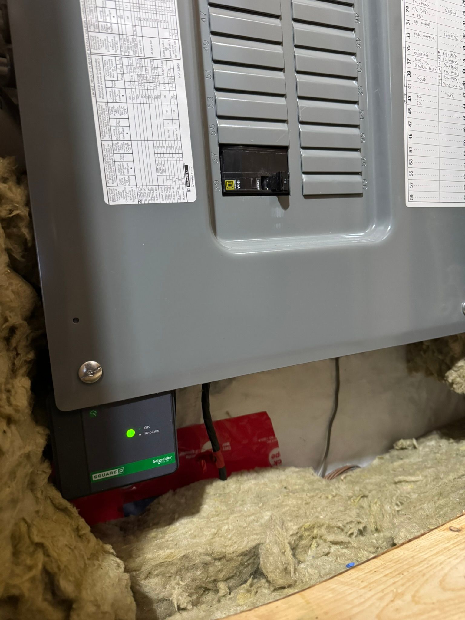 Panneau électrique gris avec dispositif vert intégré, le tout niché dans l'isolant.
