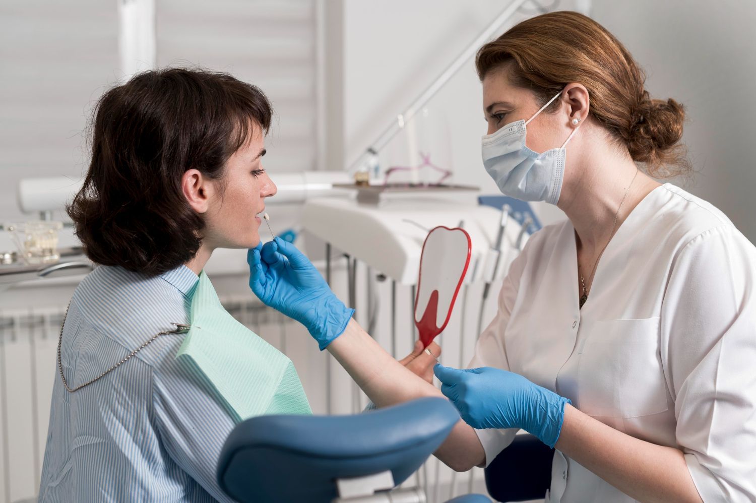 Dentist in mask and gloves examining a patient’s open mouth in a dental clinic