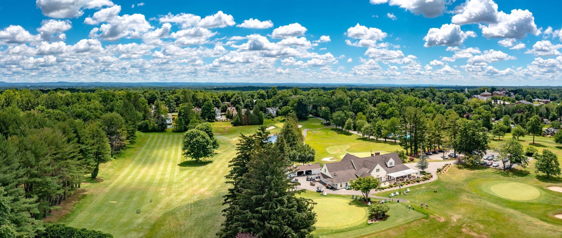 An aerial view of a lush green forest with a field in the foreground.