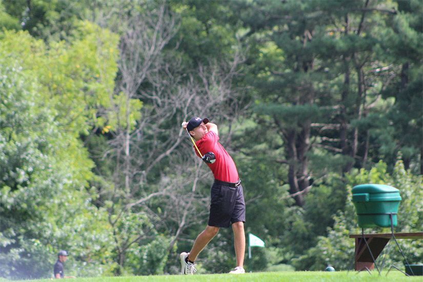 A man is swinging a golf club on a golf course.