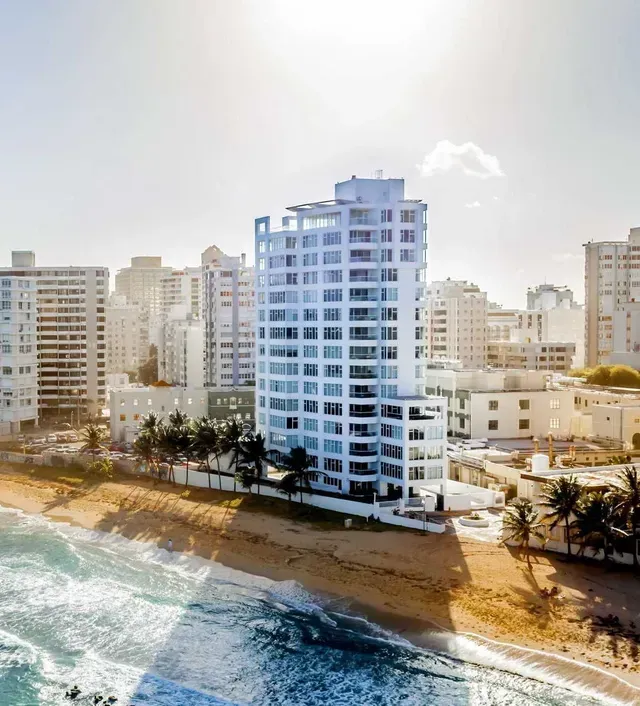 High-rise beachside apartment building overlooking a sunny shoreline and ocean waves