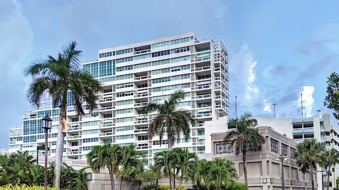Modern high-rise hotel with palm trees against a blue sky