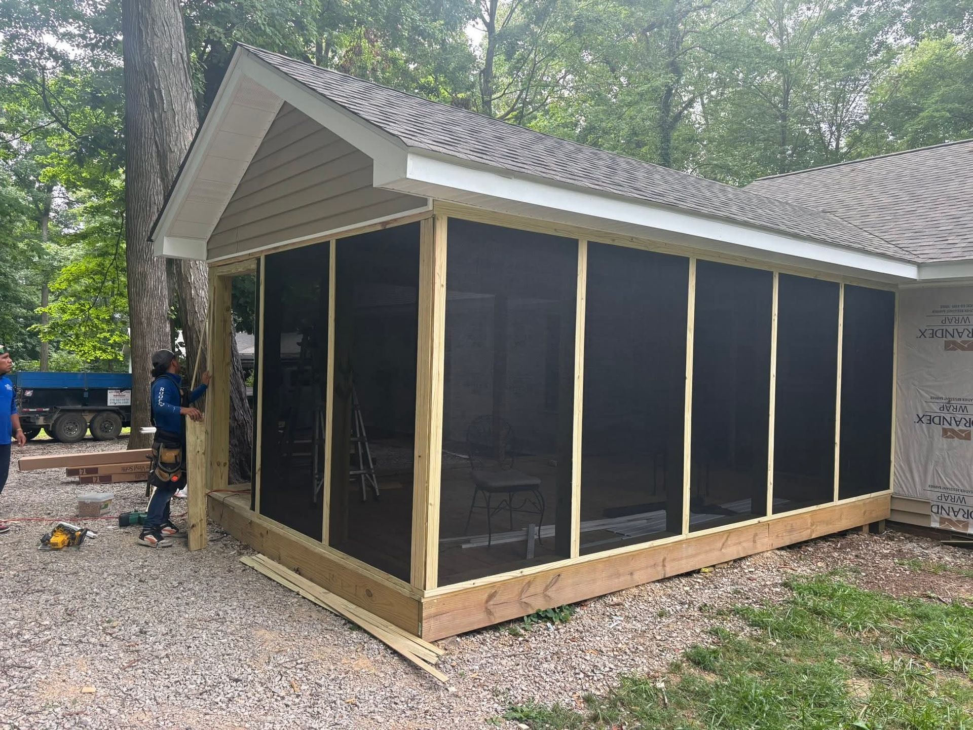 Small raised porch with a red roof and beige siding beside a white house.