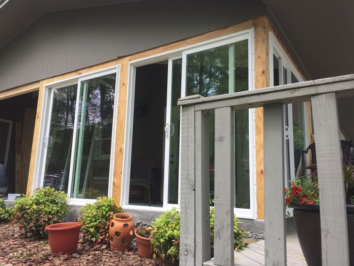 House patio with large sliding glass doors, potted plants, and a small deck railing.