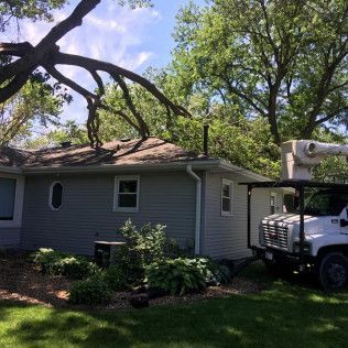 A tree trimming truck is parked in front of a house.
