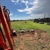 Red tractor view over a plowed field under a partly cloudy sky