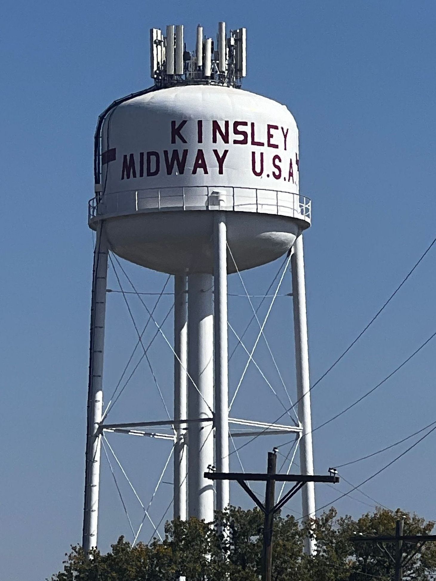 A white water tower that has kinsley midway usa written on it.