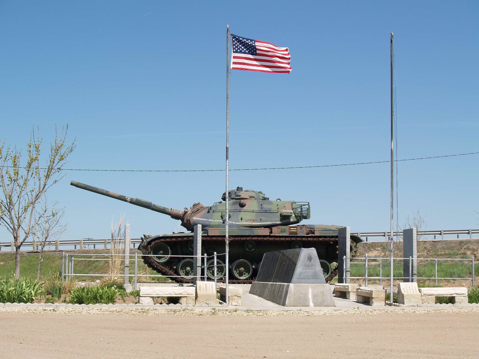 A military tank with an american flag flying in the background
