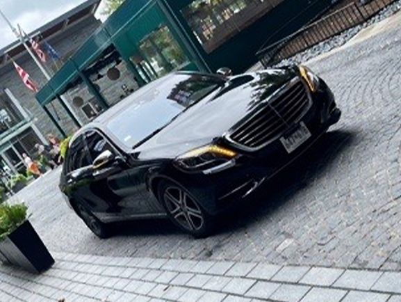 A black mercedes benz is parked on a cobblestone street