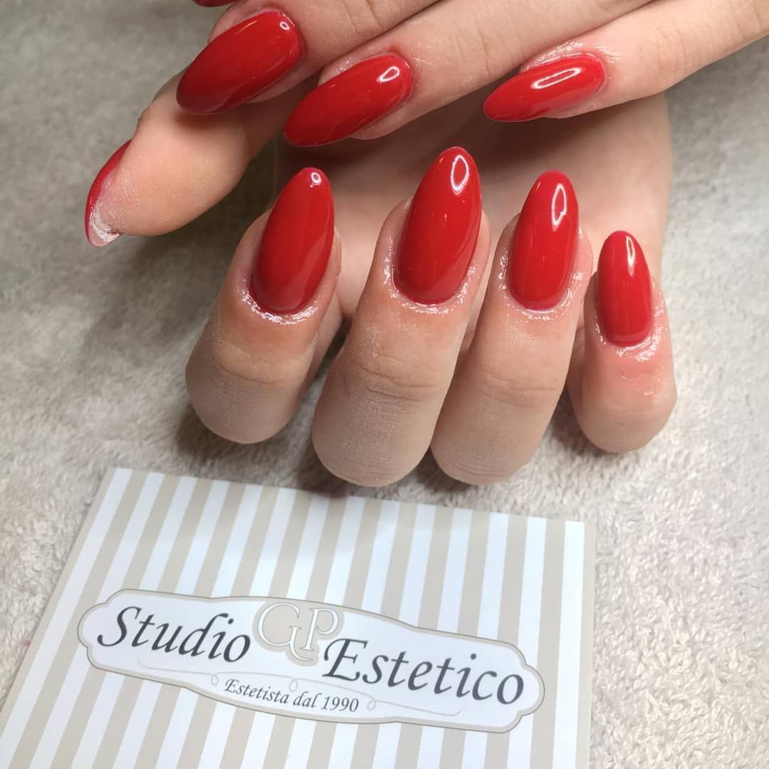 Mani di una donna con unghie rosse e un biglietto con scritto studio estetico