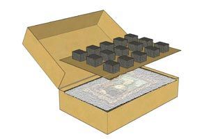 Open cardboard box with foam insert and several black cube components on top