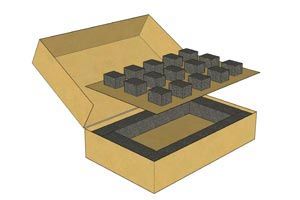 Open box with foam inserts and small black square pieces arranged above it
