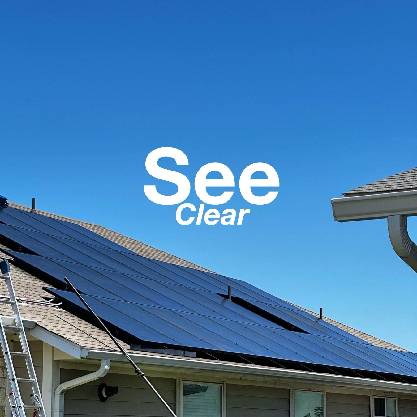 Solar panels on a roof under a blue sky with the words “See Clear” above them