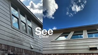 Modern home exterior with gray siding, black-framed windows, and a blue sky with clouds