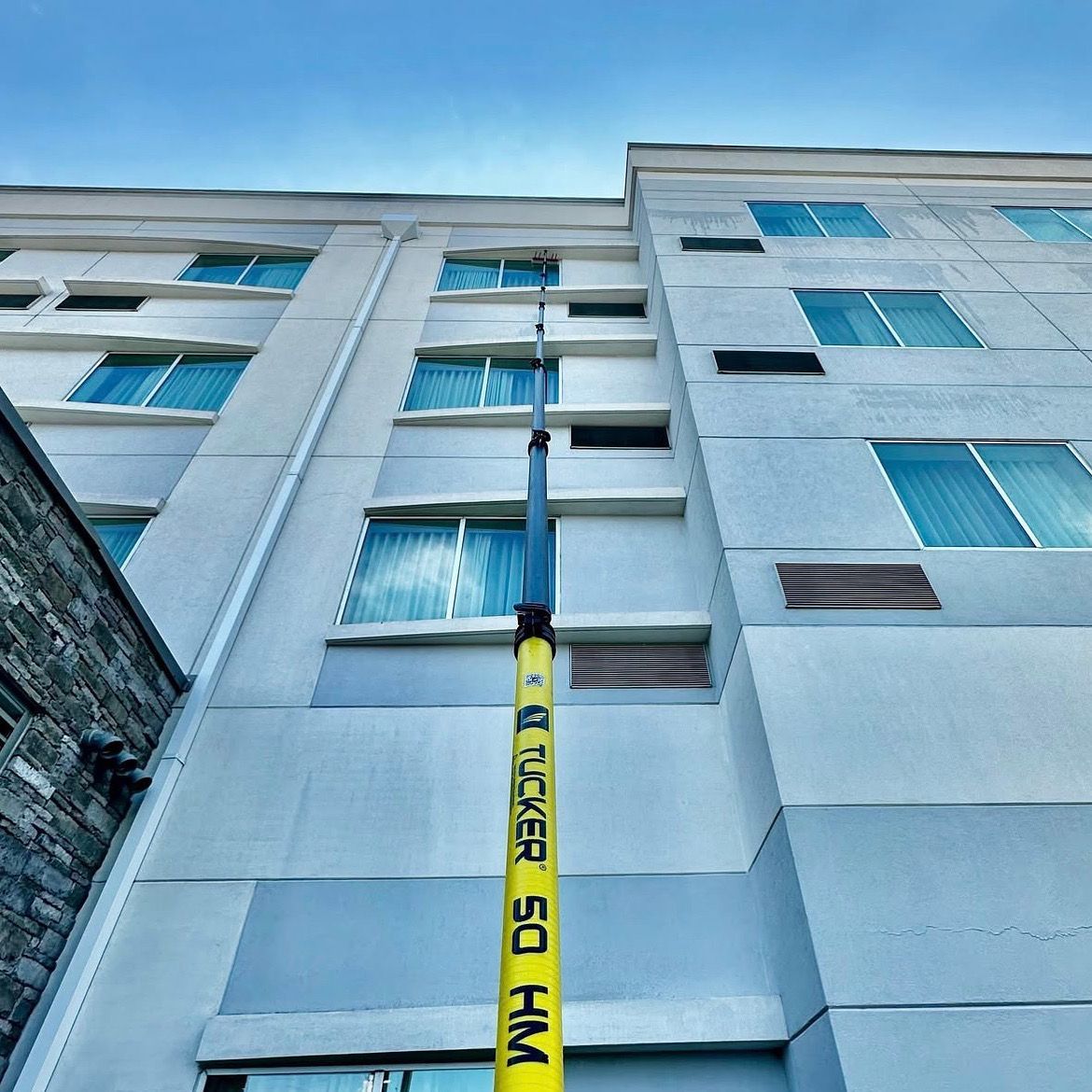 Looking up at a white multi-story building with blue windows and a yellow caution tape hanging down the center.