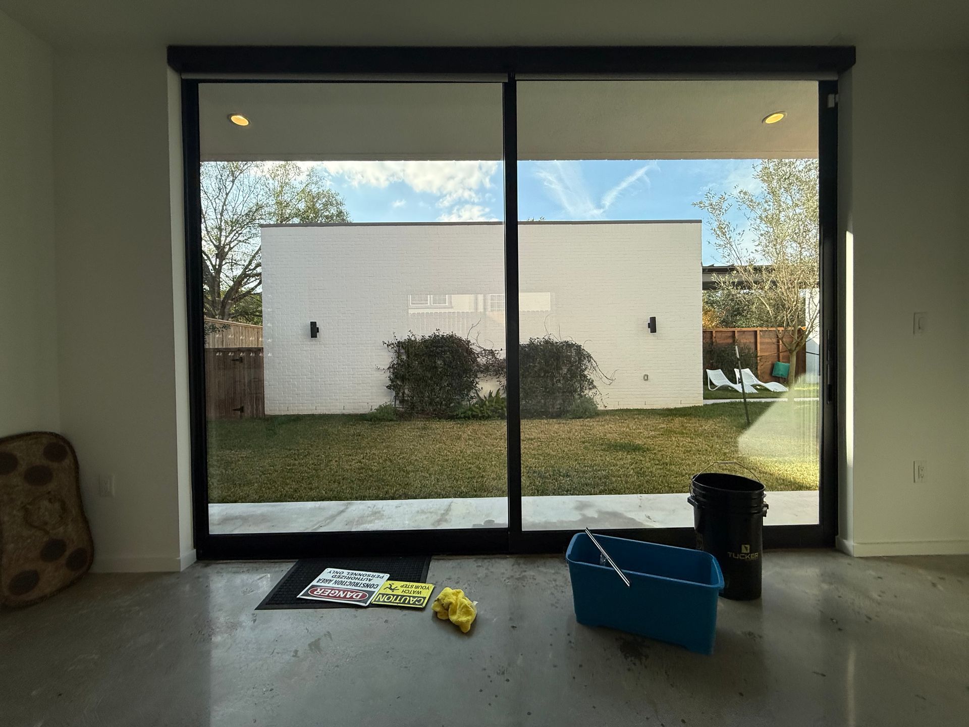 Empty room with large sliding glass doors overlooking a backyard and white outbuilding.