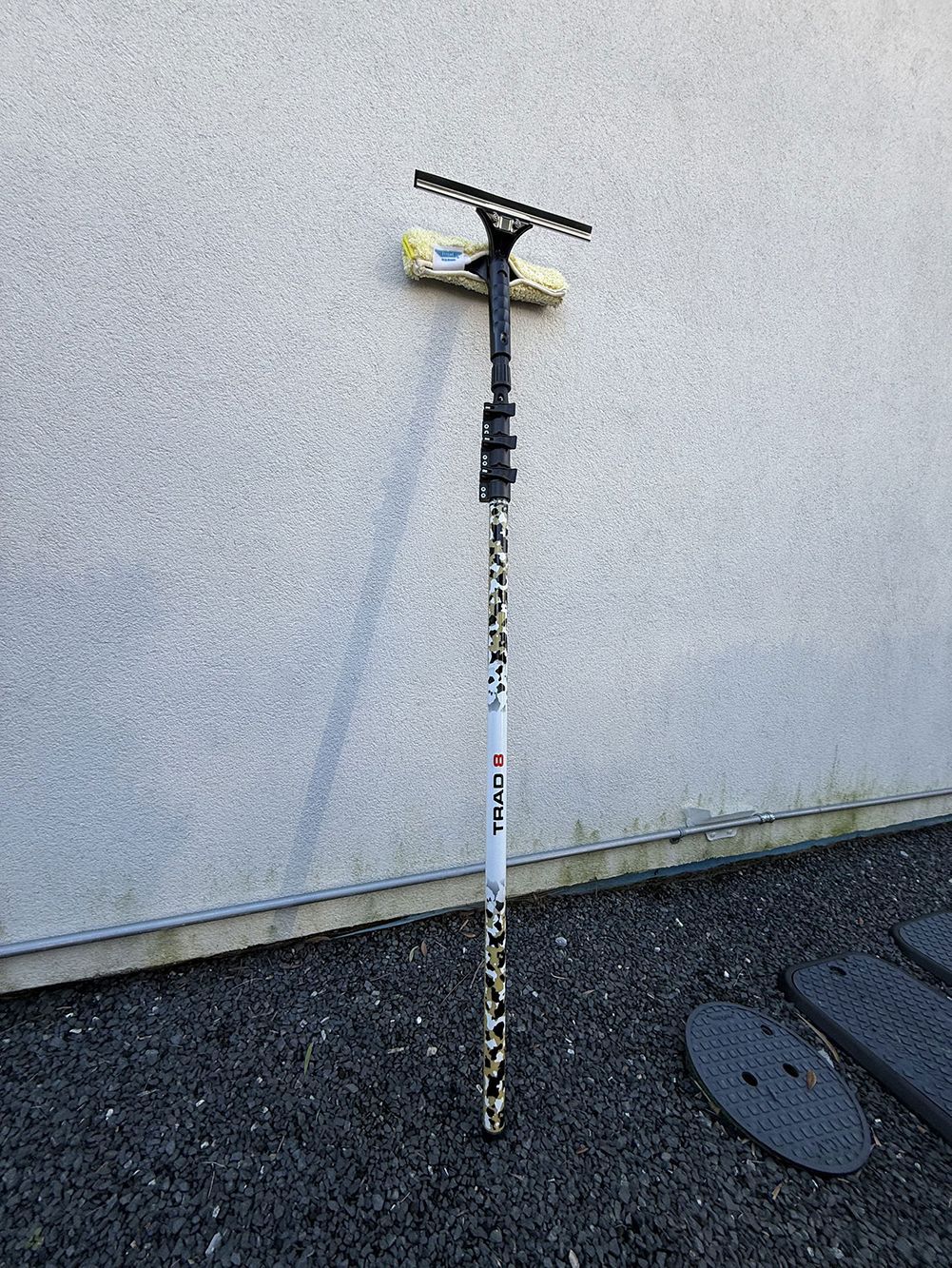 A weathered scooter standing upright against a wall on a paved surface.