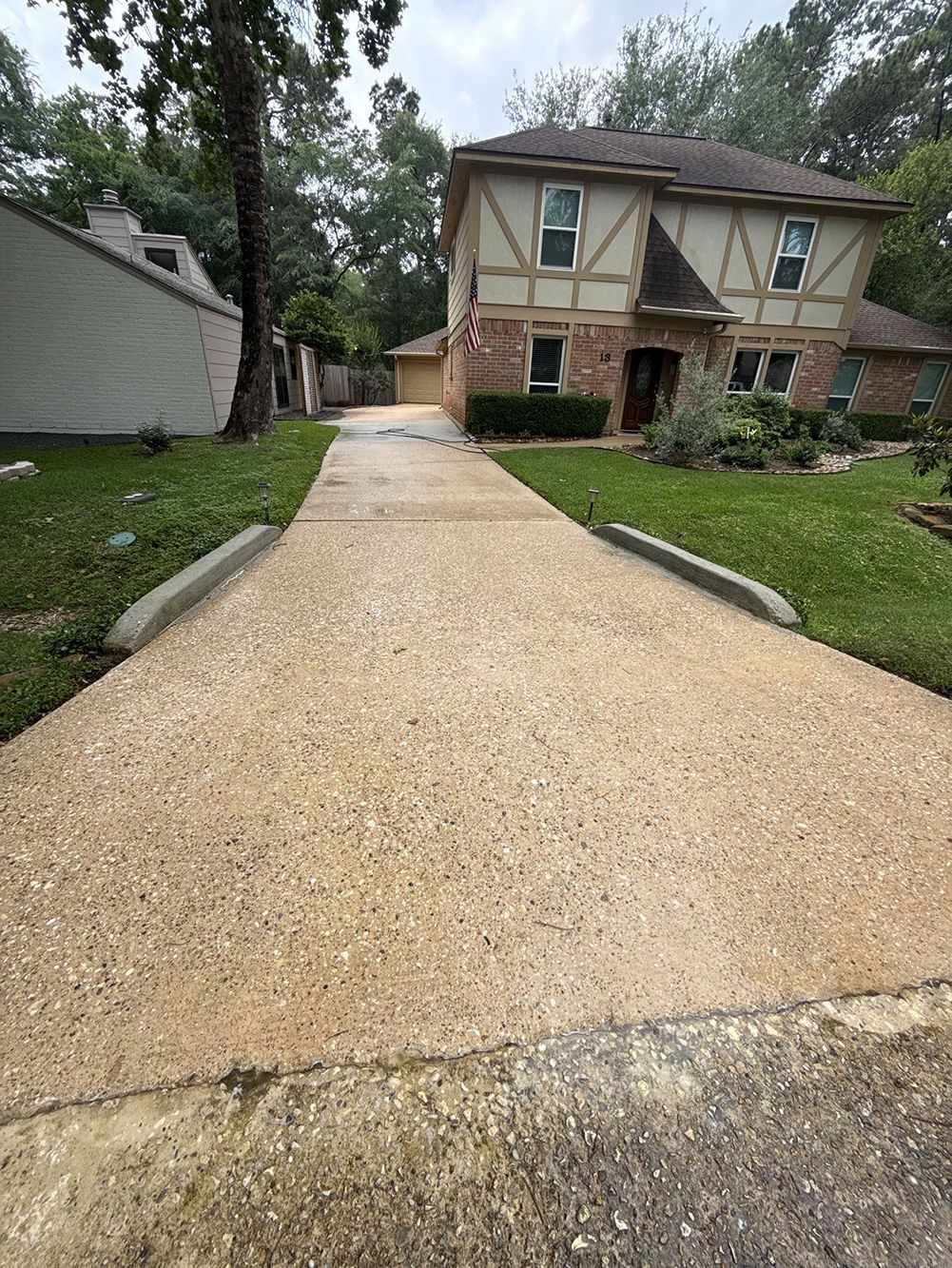 Gravel driveway leading to a two-story brick house with a green lawn and trees.