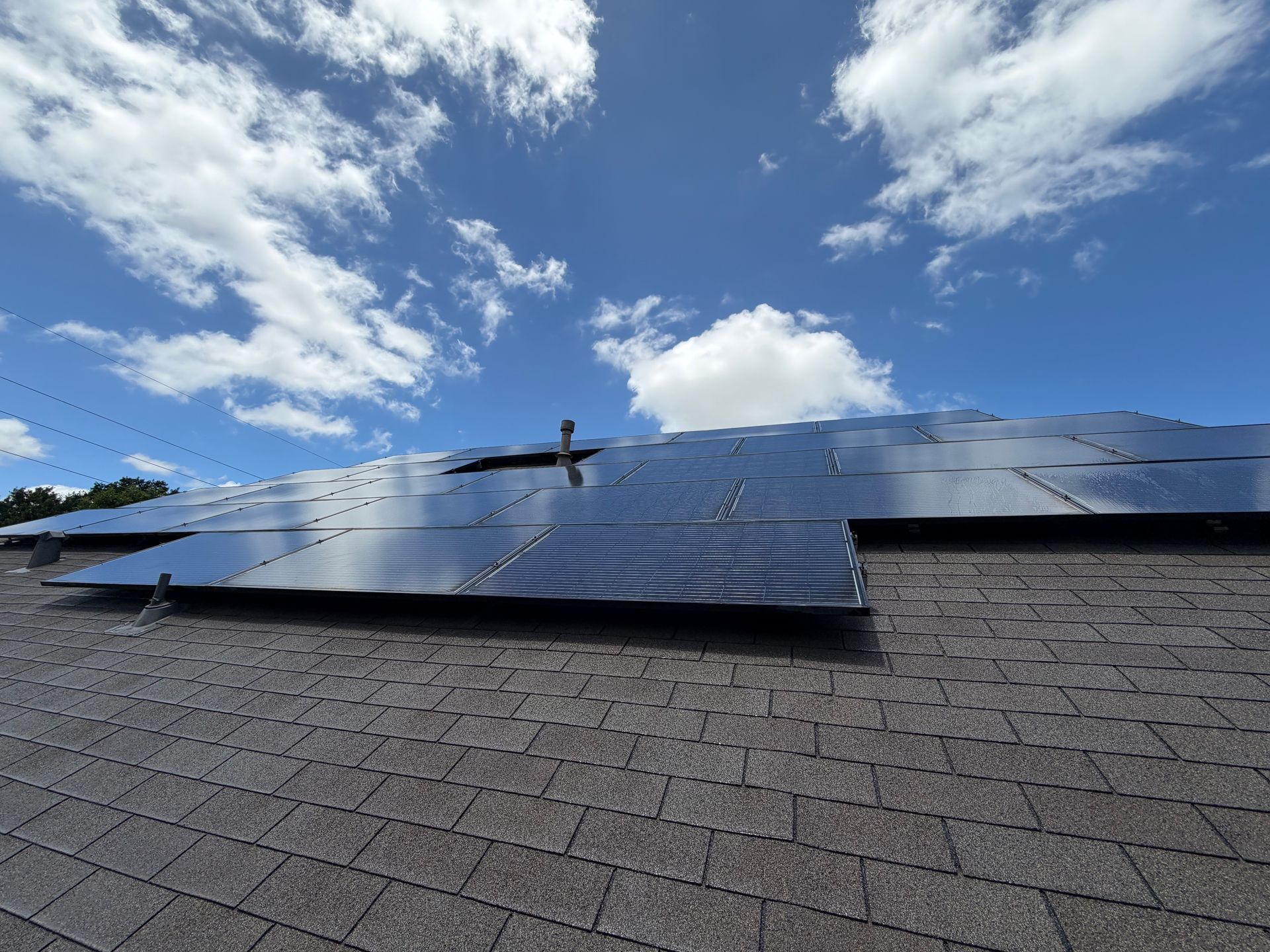 Solar panels on a rooftop under a bright blue sky with scattered white clouds.