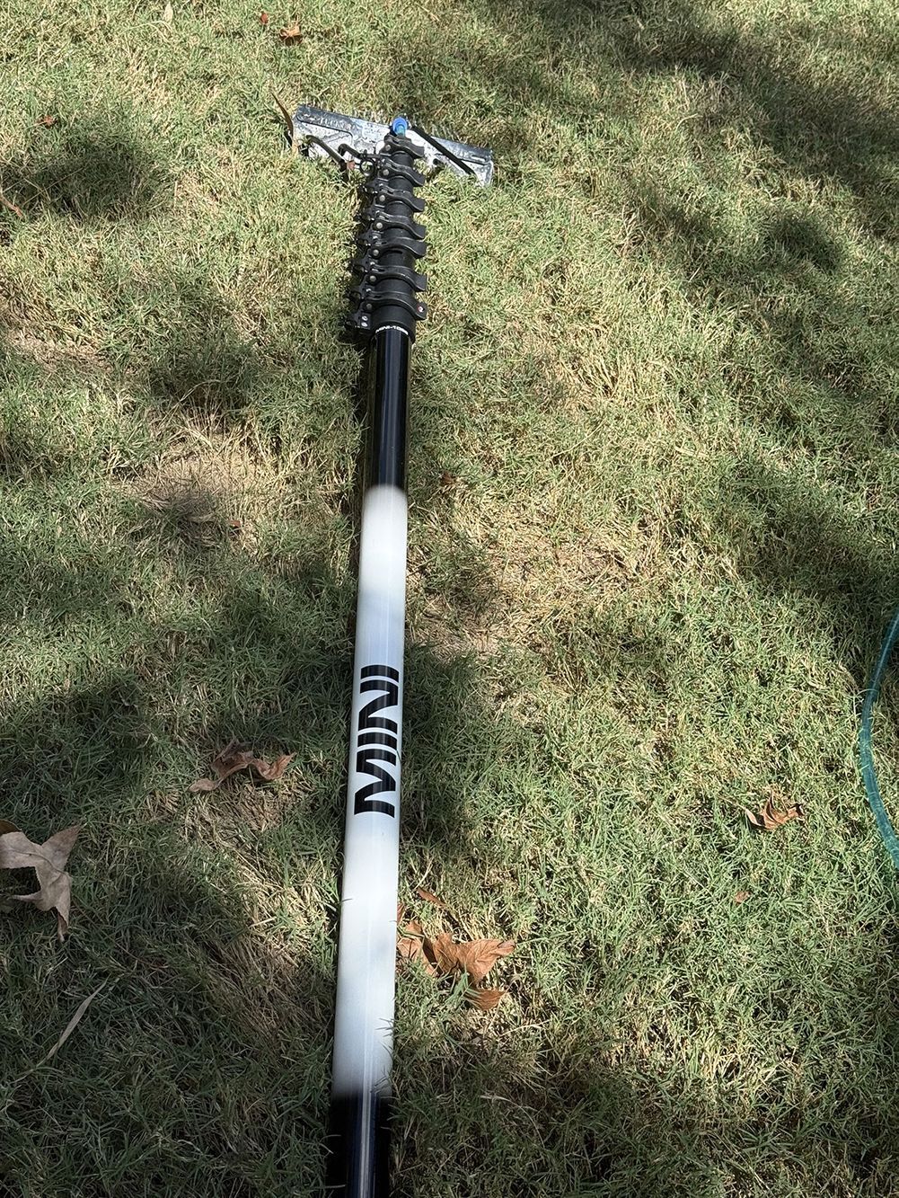 A black-and-white tool handle with a metal head lying on grass outdoors.