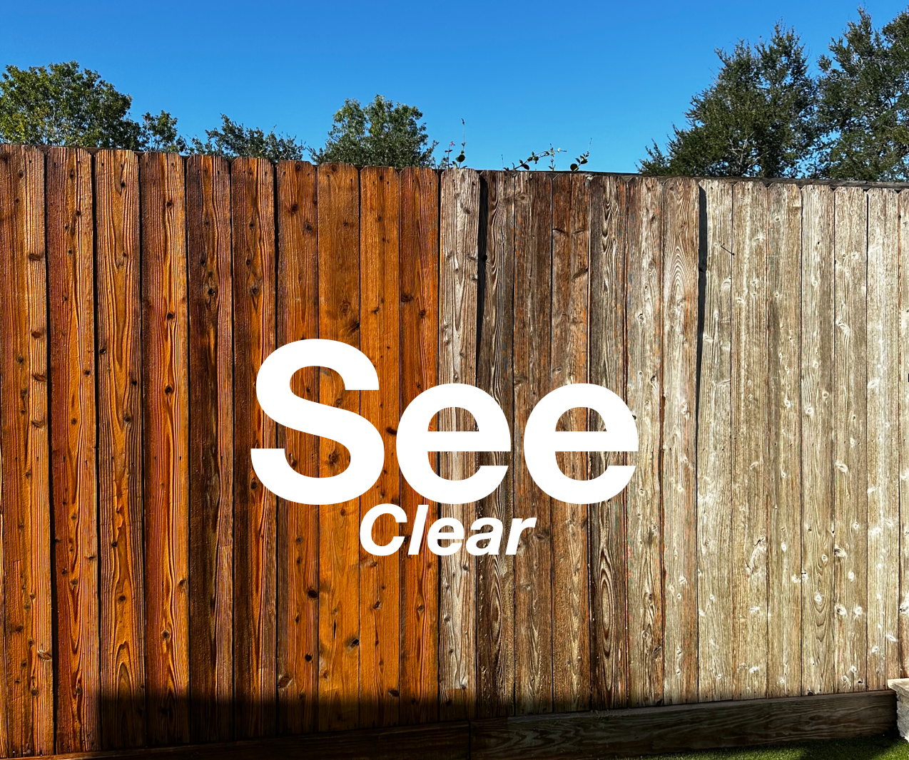 White “See Clear” text on a weathered wooden fence with orange and gray planks.