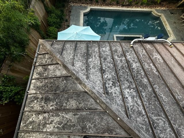 Weathered rooftop overlooking a backyard pool and a light blue patio umbrella