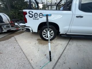 White pickup truck with a trailer and a black-and-blue signpost on a sidewalk beside it
