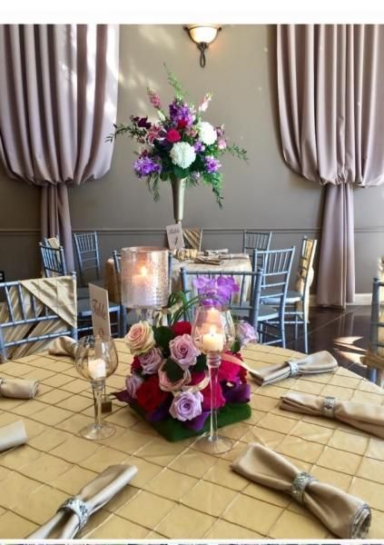 Elegant banquet table with beige linens, silver chairs, floral centerpiece, and lit candles in a formal dining room