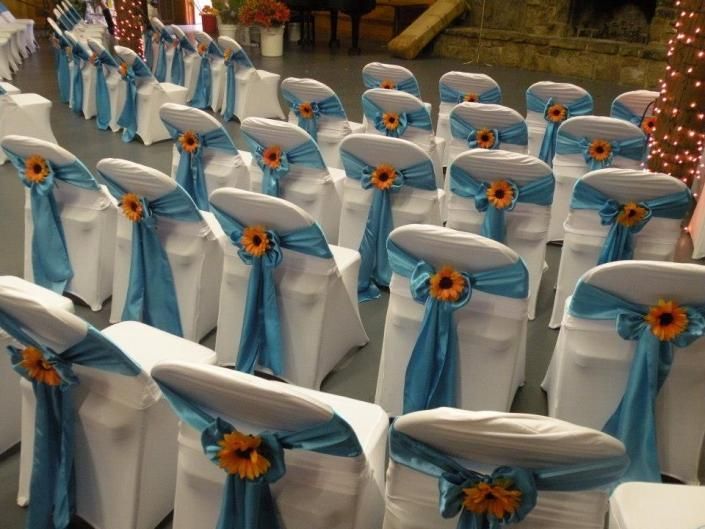 Rows of white chairs with light blue sashes and sunflower decorations at an event venue