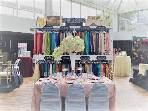 Formal dress boutique display with colorful gowns, round tables, and pink seating in a bright showroom