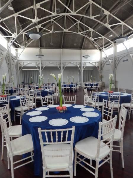 Round banquet tables with blue tablecloths and white chairs in a bright, airy event hall