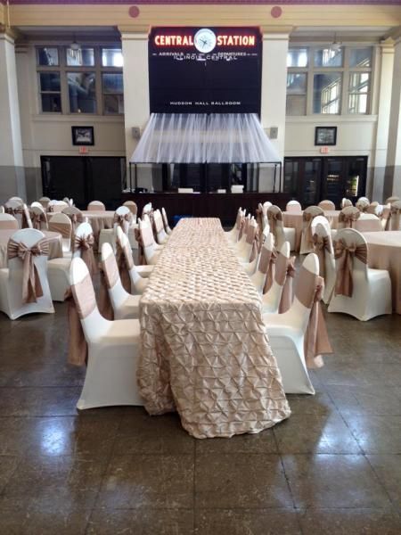 Banquet hall with long decorated tables and white chair covers arranged for an event