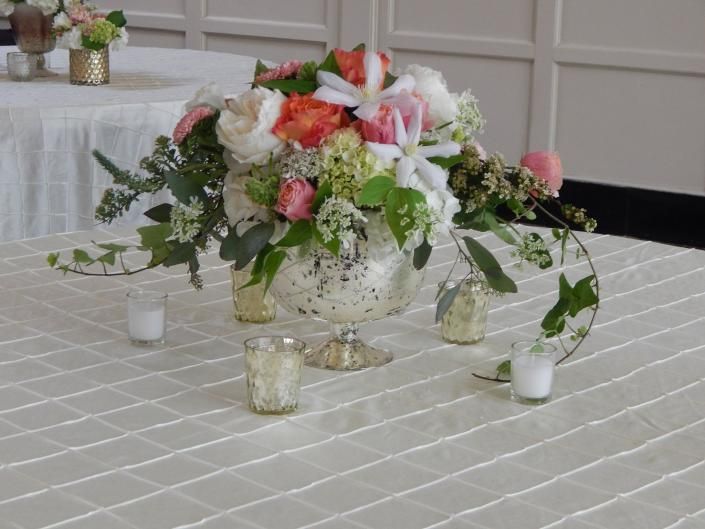 Floral centerpiece in a white vase on a checkered tablecloth, surrounded by small votive candles.