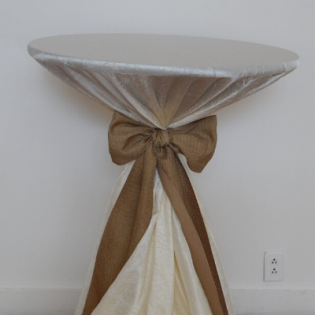 Covered table with a white cloth and brown ribbon bow against a plain wall