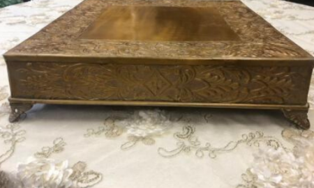 Ornate gold-colored wooden chest with carved sides on a patterned rug