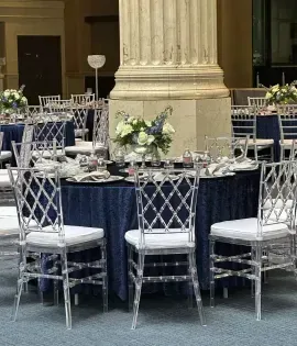 Elegant banquet table with silver chairs and floral centerpiece in a grand indoor hall
