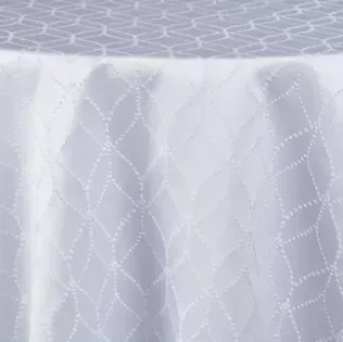 White sheer lace curtain with a delicate leaf pattern hanging over a window.