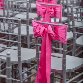 Rows of gray chairs with bright pink bows at an event venue